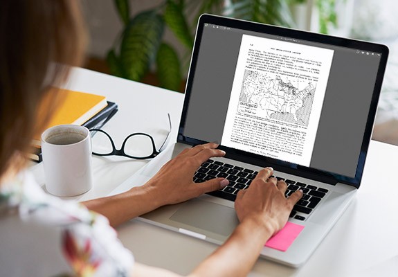 Foto: Een vrouw die op een laptop aan een document werkt